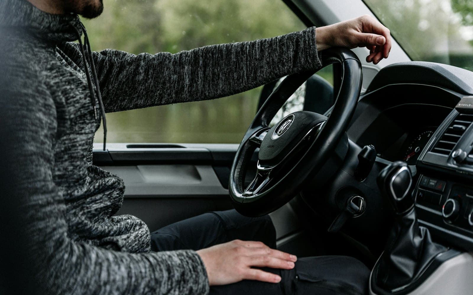 Un artisan au volant de sa camionnette, une main sur le volant.